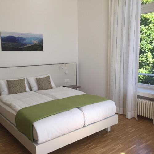a bedroom with a large white bed with a green blanket at Business Center IN Villa in Bellinzona