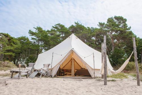a large tent on the beach with chairs and a table at Surflogiet Gotland in Tofta