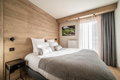 1 dormitorio con 1 cama grande y pared de madera en Apartment Kanoko Les Gets- BY EMERALD STAY, en Les Gets
