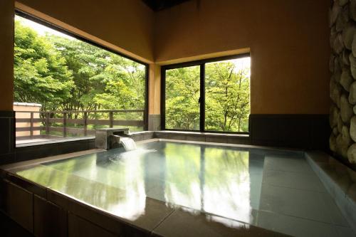 a large swimming pool with two windows in a room at Satonoyu Waraku 13 years or older in Minamioguni