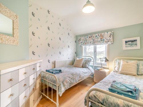 a bedroom with two beds and a window at Oak Cottage in Saxmundham