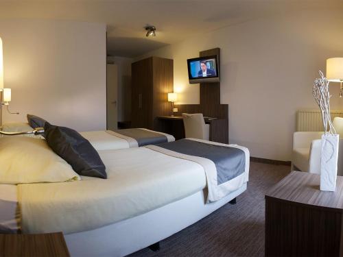 a hotel room with two beds and a flat screen tv at Hotel Asteria in Venray