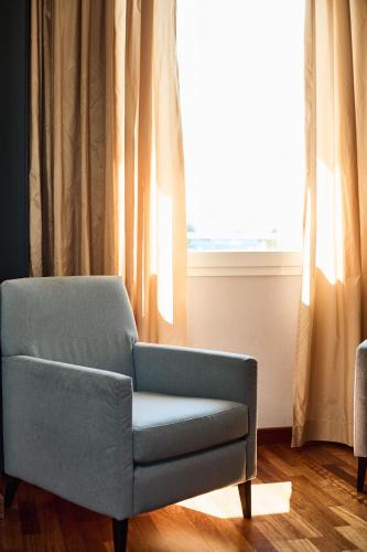 a blue chair sitting in front of a window at Hotel Da Vinci in Vinci