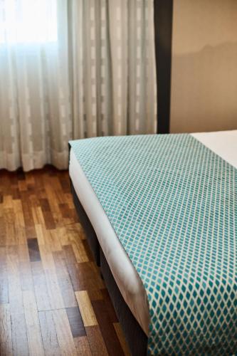 a bedroom with a bed with a green and white comforter at Hotel Da Vinci in Vinci