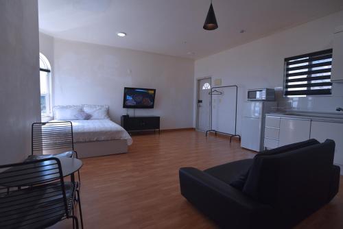 a bedroom with a bed and a kitchen and a living room at Ever Rose Pension in Namhae
