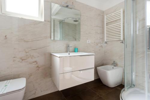 a white bathroom with a sink and a toilet at Villa Greta Hotel Rooms & Suites in Taormina