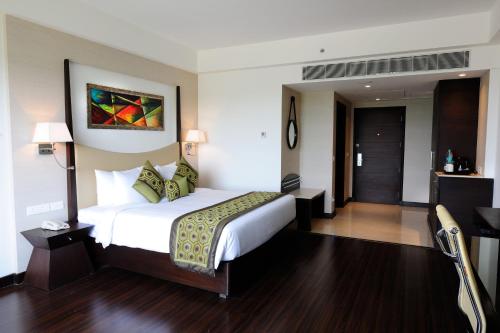 a hotel room with a large bed and a door at Gurmon Hotels Sohna Road Gurugram, a member of Radisson Individuals in Sohna