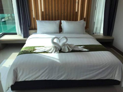 a bedroom with a bed with a white bow on it at Boat House Boutique Riverside in Talat Amphoe Nakhon Chai Si