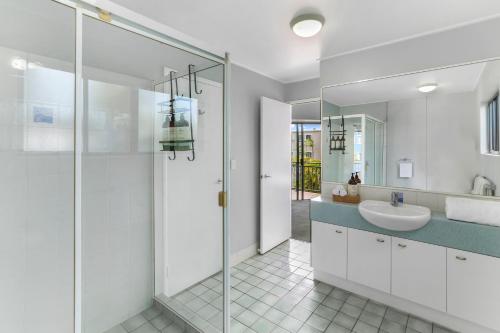 a white bathroom with a sink and a shower at Unit 41 at Portobello Dicky Beach in Caloundra