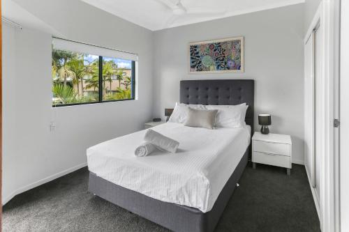 a white bedroom with a large bed and a window at Unit 41 at Portobello Dicky Beach in Caloundra