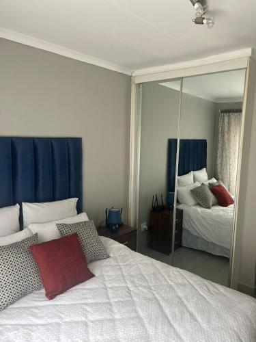una camera con letto bianco e specchio di Rosa on St James a Johannesburg