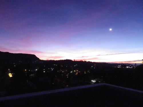 a night view of a city with the moon in the sky at MANUDI Glenfallsedge Rest in Nuwara Eliya