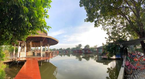a river with a boat house on the water at Boat House Boutique Riverside in Talat Amphoe Nakhon Chai Si