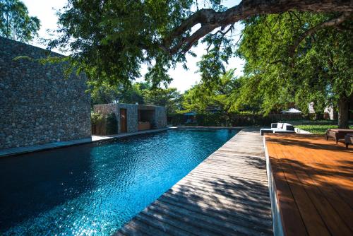 a swimming pool with a wooden deck next to a house at Tolani Resort Kui Buri in Kui Buri