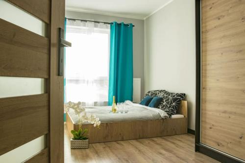 a bedroom with a bed with blue curtains and a window at Apartament Nowa Grunwaldzka in Suwałki