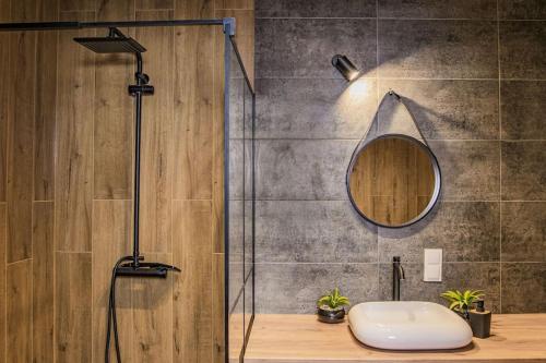 La salle de bains est pourvue d'une douche, d'un lavabo et d'un miroir. dans l'établissement Apartament Nowa Grunwaldzka, à Suwałki