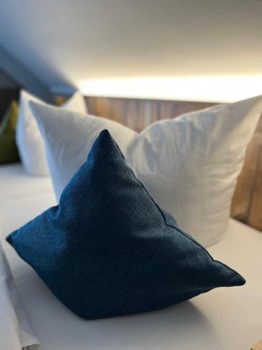 a black pillow sitting on a bed with pillows at Gasthaus-Pension Hofmann in Oberdachstetten