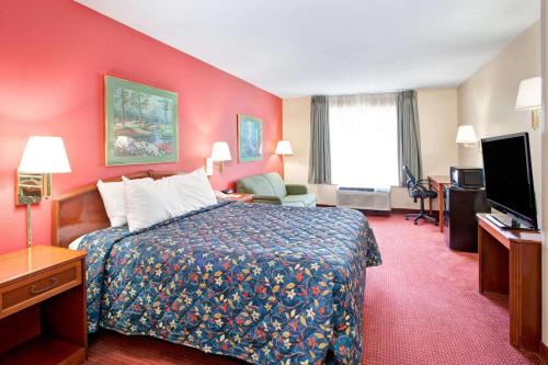 a hotel room with a bed and a flat screen tv at Days Inn by Wyndham Marietta-Atlanta-Delk Road in Marietta