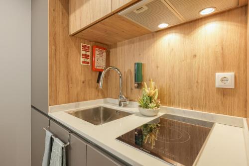 a kitchen with a sink and wooden walls at Signature Aveiro Flat incl Parking by Home Sweet Home Aveiro in Aveiro