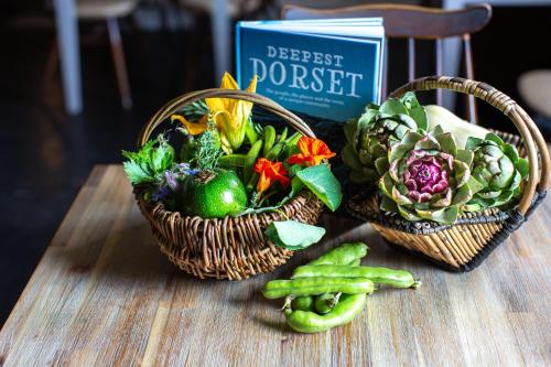 two baskets of vegetables on a table with a book at La Fosse at Cranborne in Cranborne