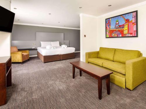 a hotel room with a bed and a couch at Mercure Chester Abbots Well Hotel in Chester