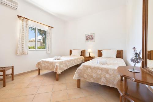 - une chambre avec 2 lits, une table et une fenêtre dans l'établissement Casa da Bia by OCvillas, à Albufeira