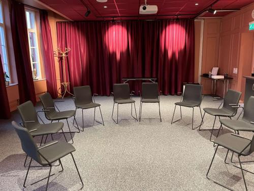 a room with chairs and a stage with red curtains at Statt Hassleholm BW Signature Collection in Hässleholm
