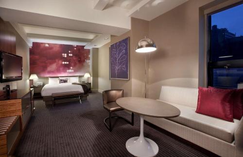 a hotel room with a bed and a couch and a table at Hyatt Grand Central New York in New York