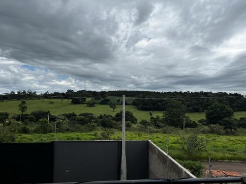 a view of a green field with a cloudy sky at Container-Spa quente, projetor cine, lareira, churrasqueira-20km de Brotas in Torrinha