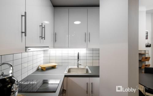 - une cuisine avec des placards blancs et un évier dans l'établissement CityLiv Apartment by LobbySquare, à Athènes