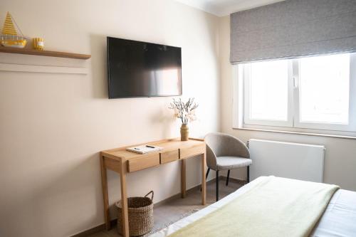 a bedroom with a desk and a tv on the wall at Rising Sun Westende in Middelkerke
