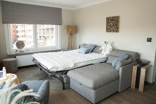 um quarto com uma cama, um sofá e uma janela em Rising Sun Westende em Middelkerke