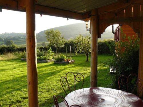 a table on a porch with a view of a yard at La Roulotte de la Fay in Dompierre-les-Ormes