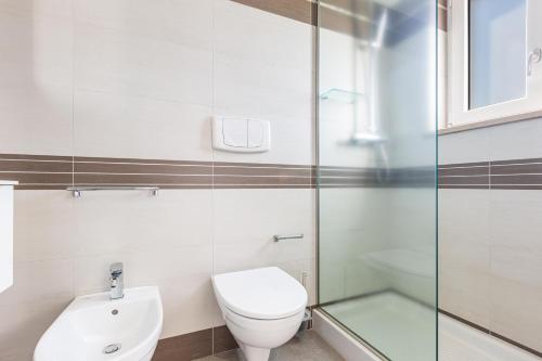 a bathroom with a toilet and a glass shower at Attico Mezzaluna by BarbarHouse in Torre Santa Sabina