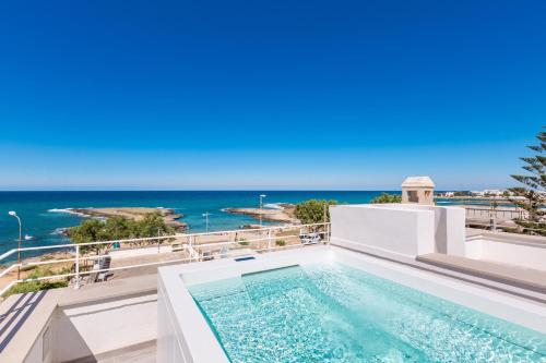 a swimming pool on top of a building with the ocean in the background at Attico Mezzaluna by BarbarHouse in Torre Santa Sabina
