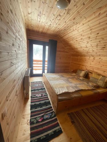een groot bed in een houten kamer met een raam bij Aroa Mountain in Zărneşti