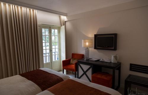 a hotel room with two beds and a desk and a television at Josefa D`Obidos Hotel in Óbidos