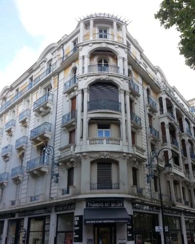 un edificio blanco alto con balcones en una calle en Magnifique Appartement - Hôtel du Parc - VICHY, en Vichy