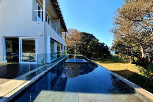 a swimming pool in front of a house at Splash Rock Beachfront Villa in Umtentweni