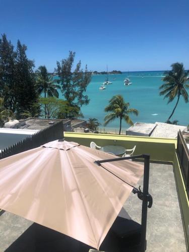 an umbrella on a balcony with a view of the water at Ocean-view penthouse with roof terrace, Grand Baie, Waterside complex in The Vale