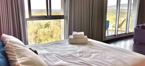 uma cama branca num quarto com uma grande janela em Sea view apartment with Jacuzzi near beach em Nahariya