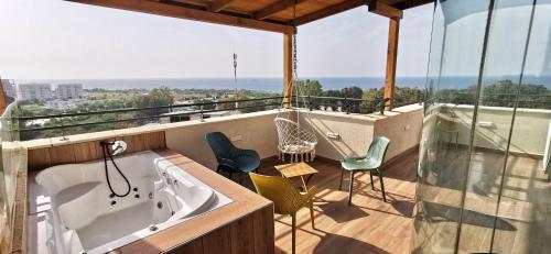 a bath tub sitting on a balcony with chairs at Sea view apartment with Jacuzzi near beach in Nahariyya