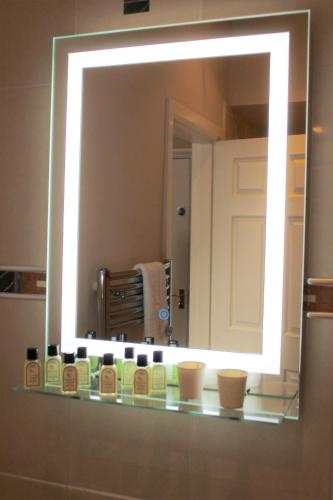 a mirror in a bathroom with a shelf with products at The Crown Hotel in Morecambe
