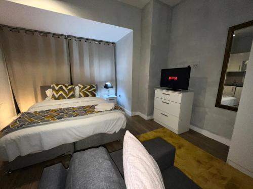 een slaapkamer met een bed en een tv en een bank bij Moorfield Liverpool City Studios in Liverpool