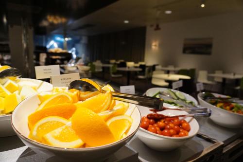 a buffet with bowls of oranges and tomatoes on a table at First Hotel Jönköping in Jönköping