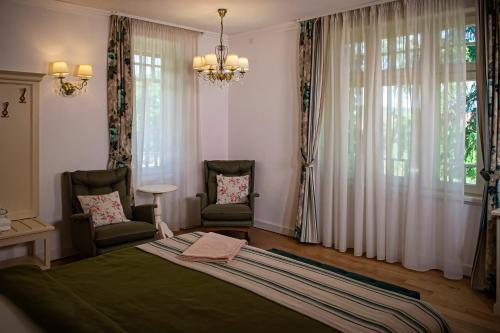 een slaapkamer met een groot bed en 2 stoelen bij Vila Rozalia Garden Gate in Avrig
