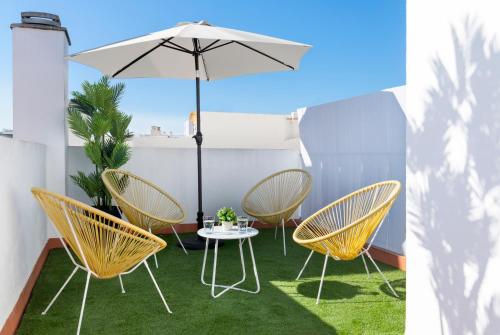 a patio with a table and chairs and an umbrella at Magno Apartments Redes Terrace in Seville