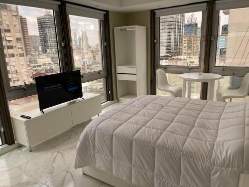 1 dormitorio con 1 cama, TV y ventanas en Hermoso departamento, increible vista. en Buenos Aires