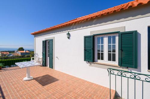 a white house with green shutters and a balcony at CASA BACELAR in Afife