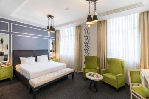 a bedroom with a bed and two green chairs at Dondar Hotel Formula 1 View in Baku